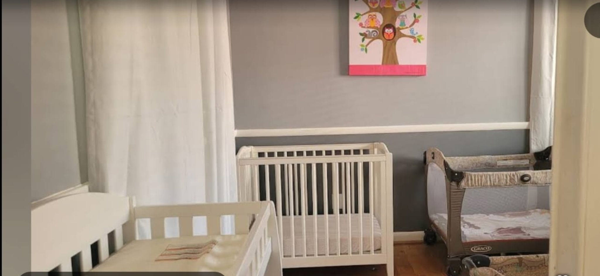 Cribs and a playard in a nursery with an owl wall art piece
