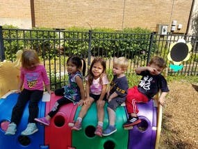 Five children sitting on colorful playground equipment