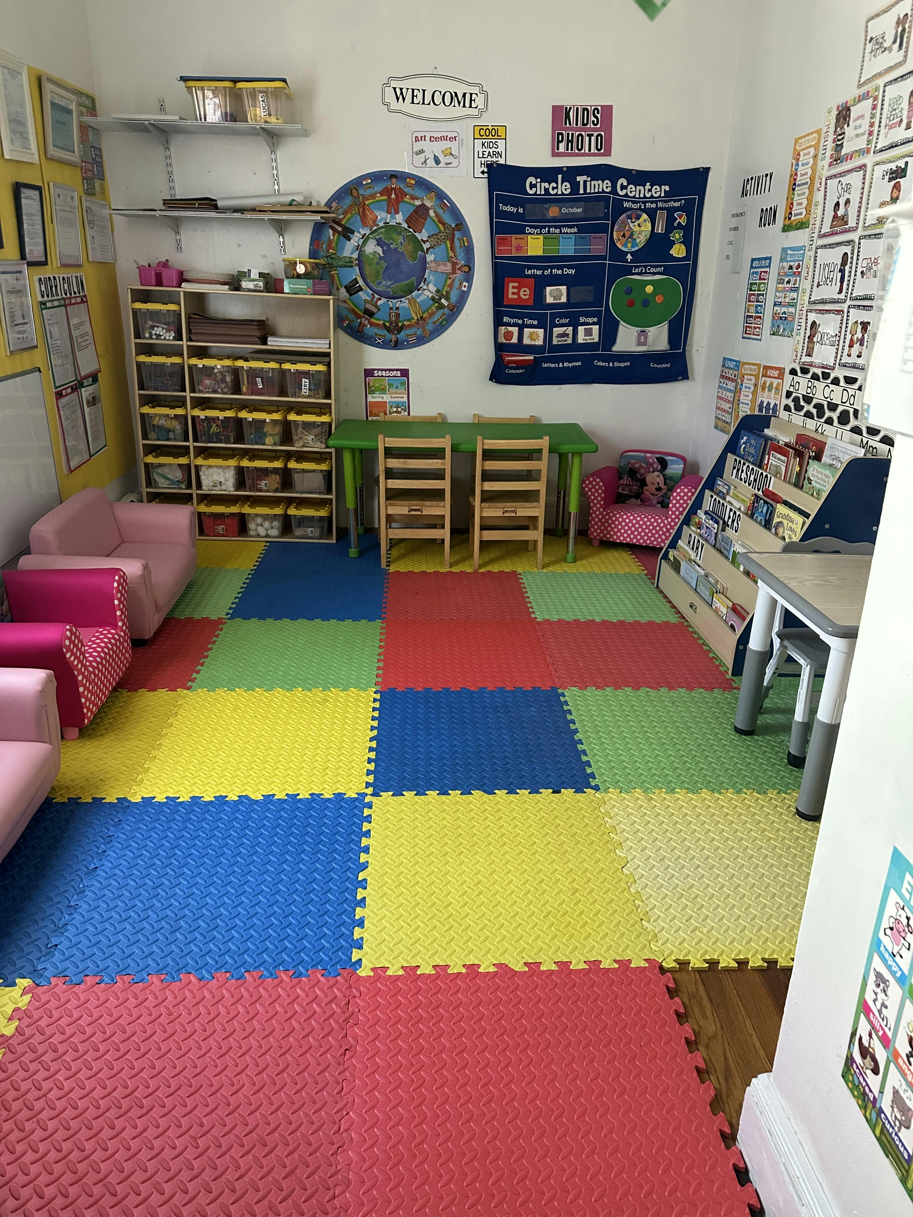 Classroom with colorful floor mats, small tables, chairs, and shelves