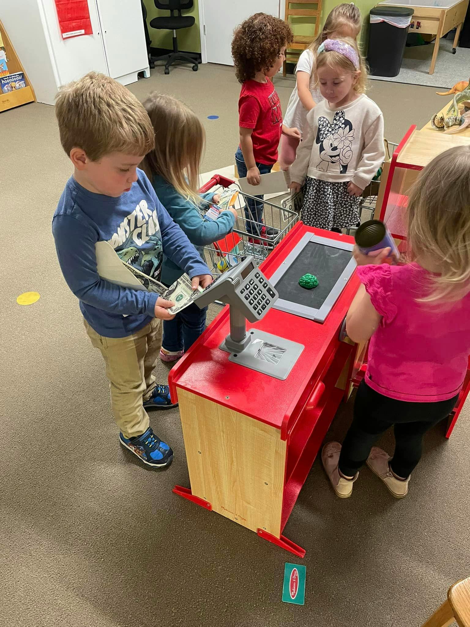 Children playing with a toy cash register and play money