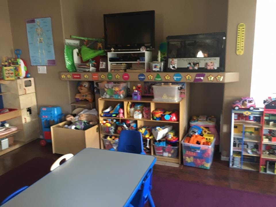 Classroom with shelves of toys, a table, and two televisions