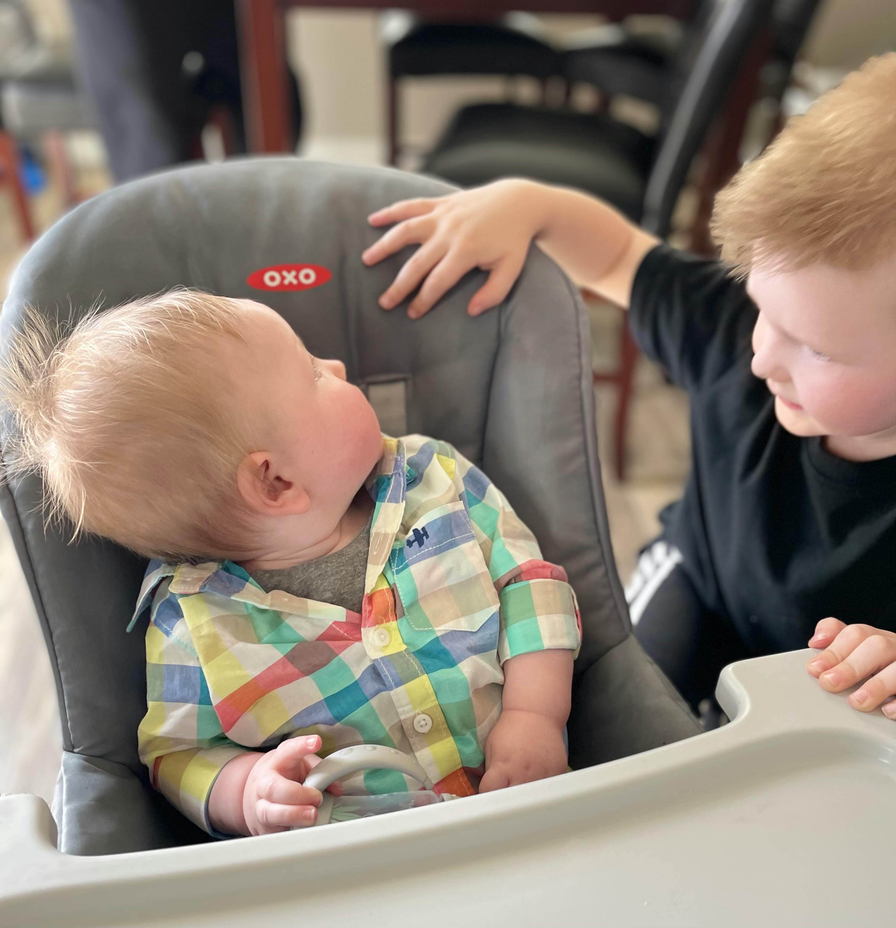 Child in high chair looking at teen