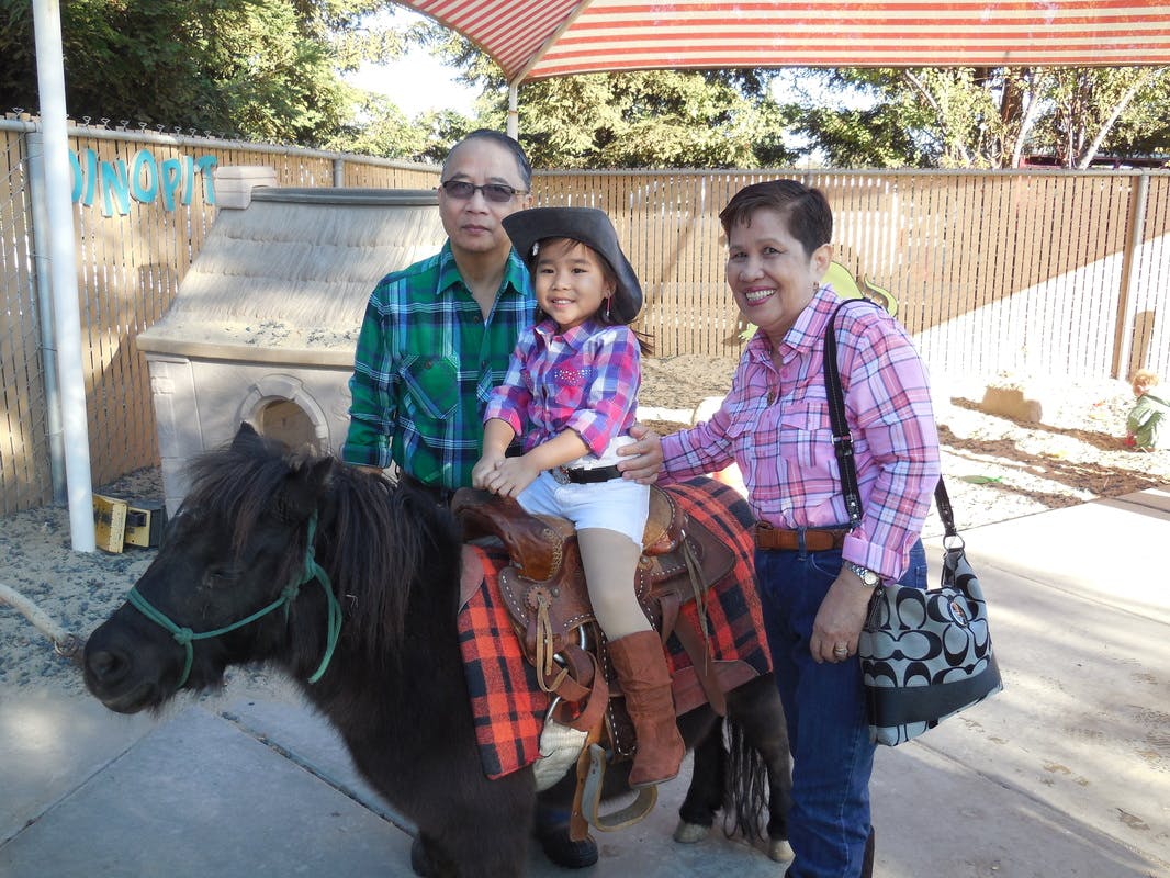 Child on a pony with two adults standing nearby