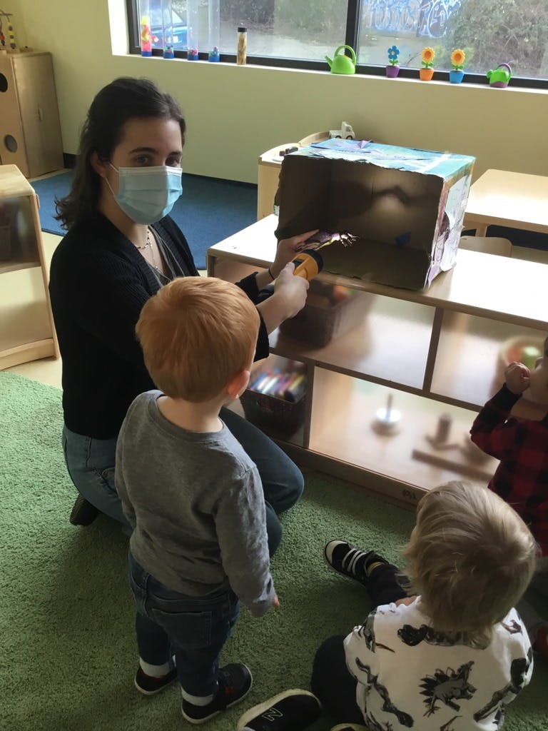 Person in mask holding a flashlight into a box for children