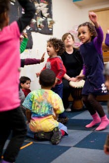 Children and an adult playing music and dancing in a classroom