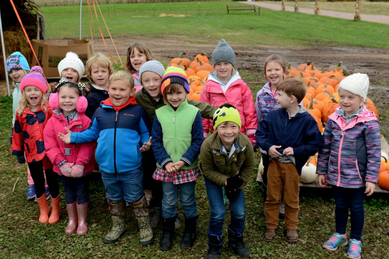 Group of children standing in front of pumpkins