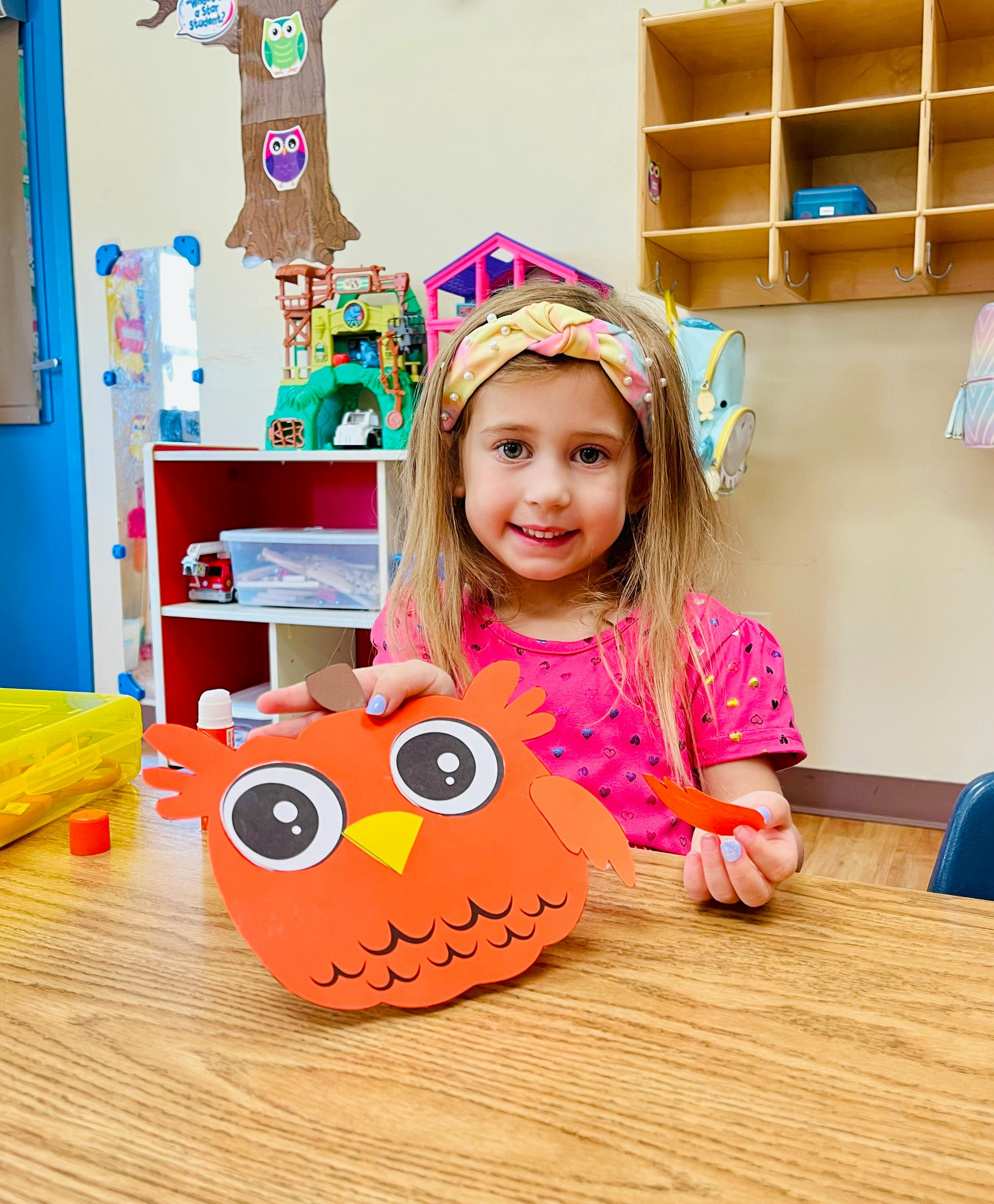 Child making an owl craft in a classroom