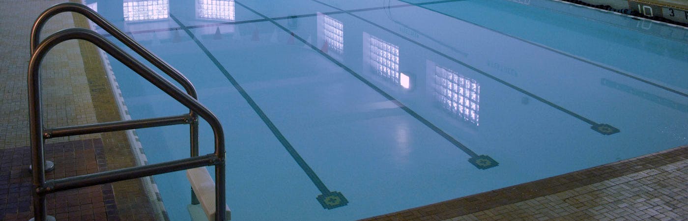 Lanes of a swimming pool with a metal handrail entering the water