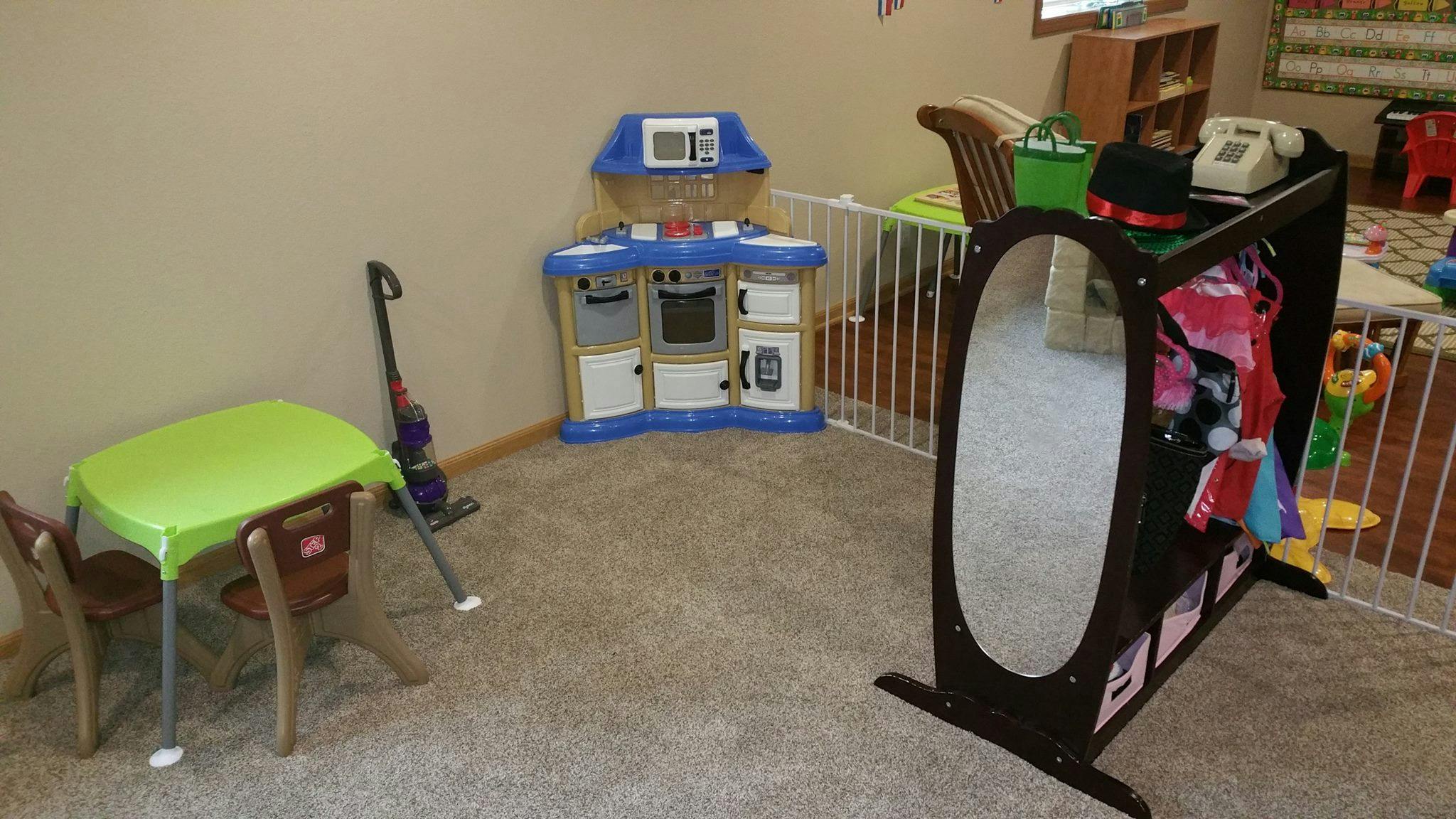 Playroom with toy kitchen, small table and chairs, and dress-up rack