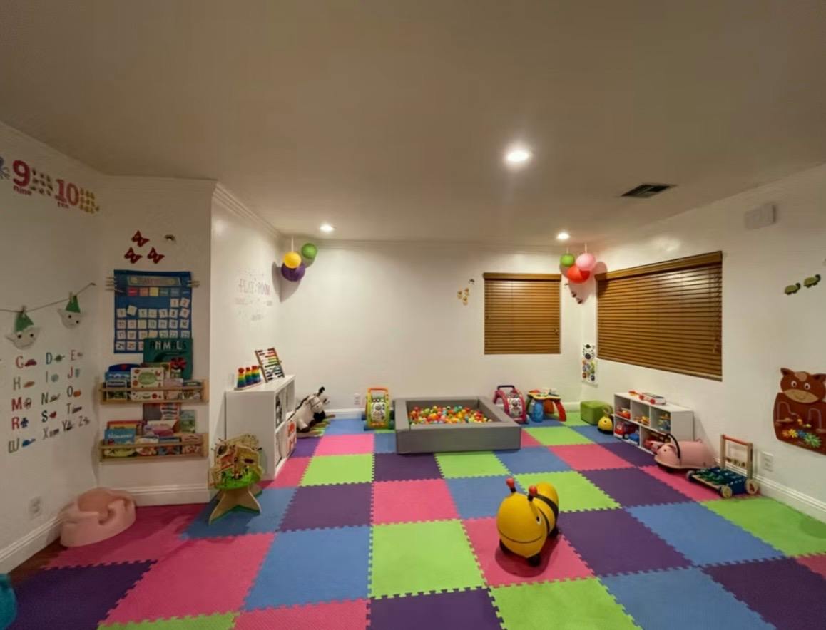 Playroom with colorful floor mats, a small ball pit, and various toys