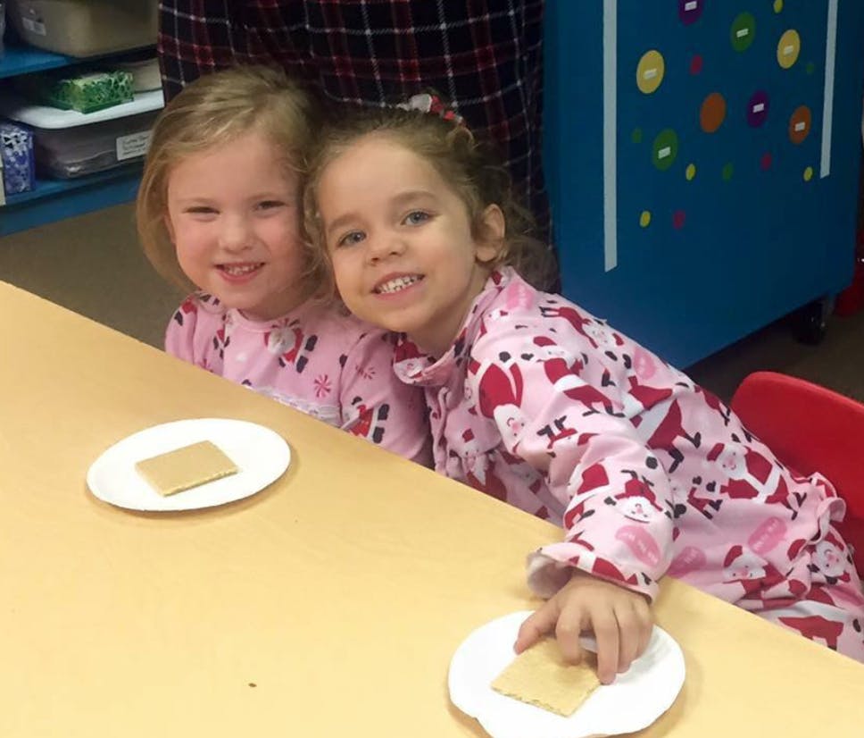 Two children in pajamas sitting at a table with plates