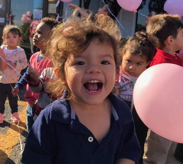 Child with open mouth and other children with balloons