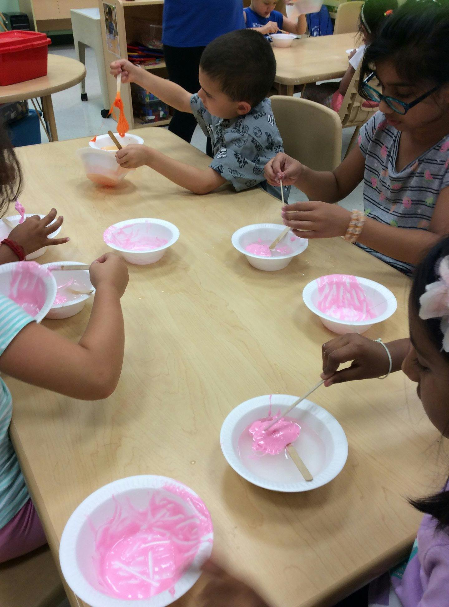 Children at a table with bowls of pink liquid