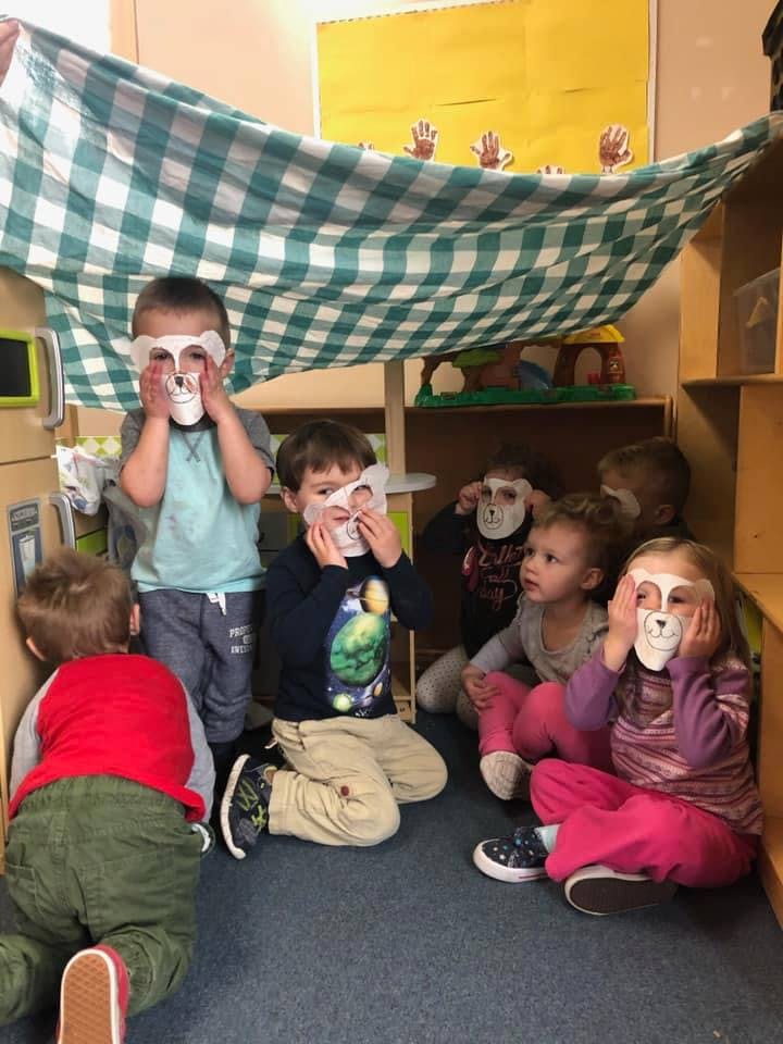 Children wearing animal masks under a blanket fort