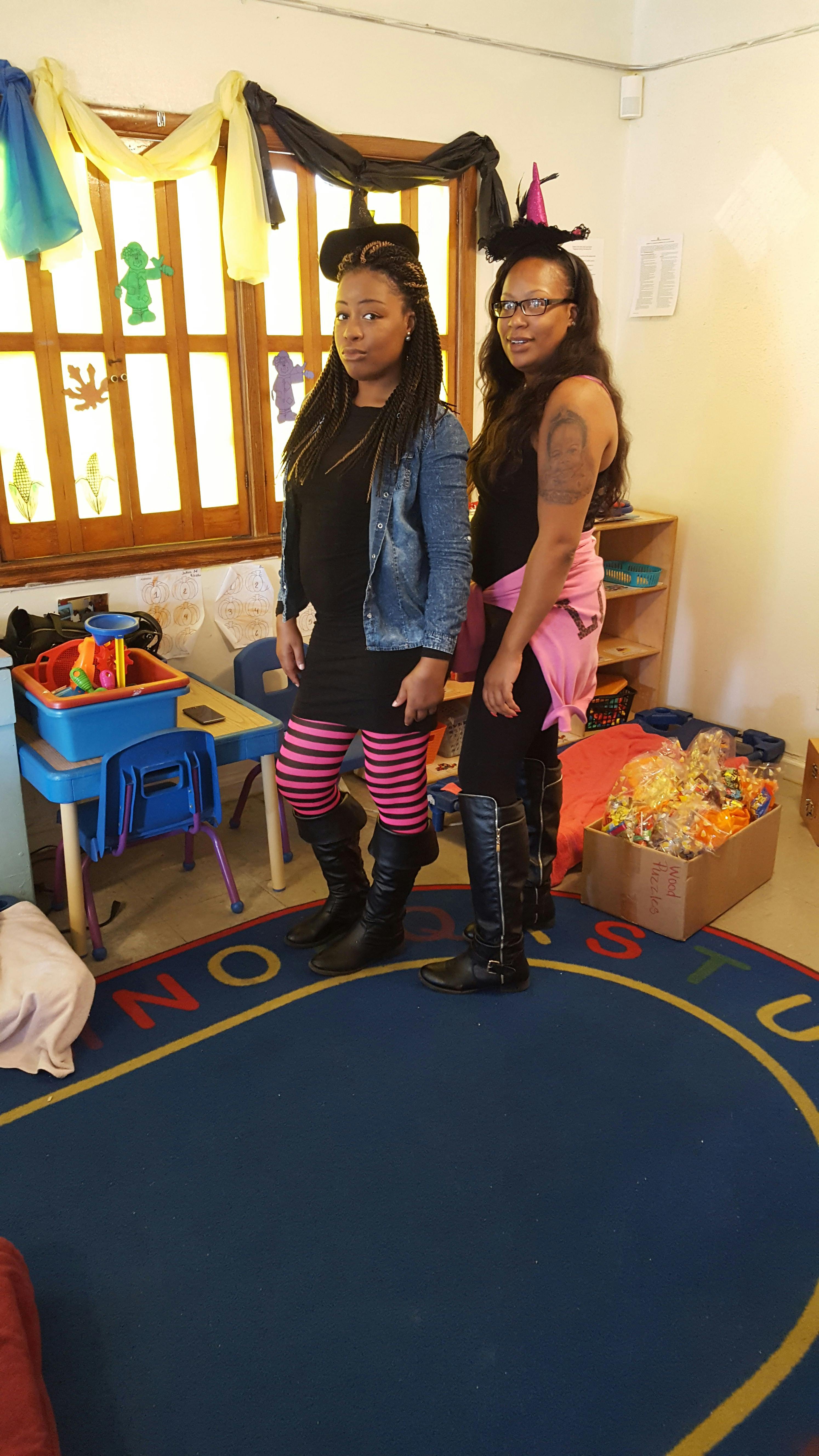 Two people in witch hats standing in a classroom