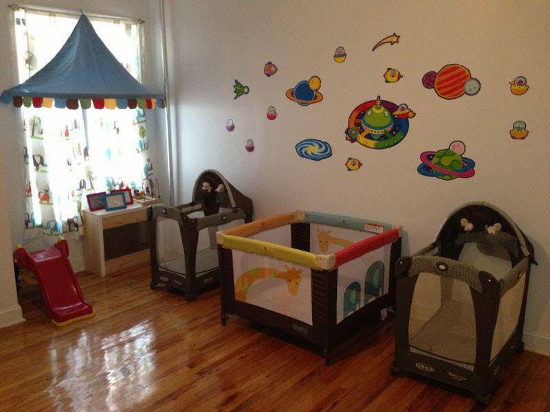 Three playpens in a room with space-themed wall decals