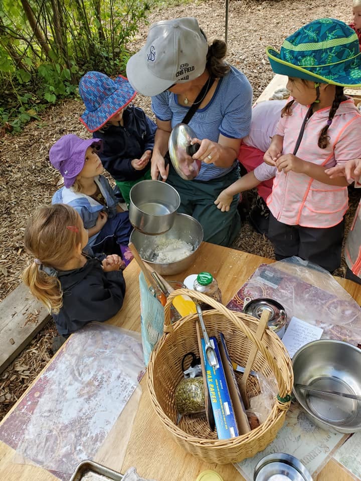 Adult and children gathered around a table with bowls and cooking utensils
