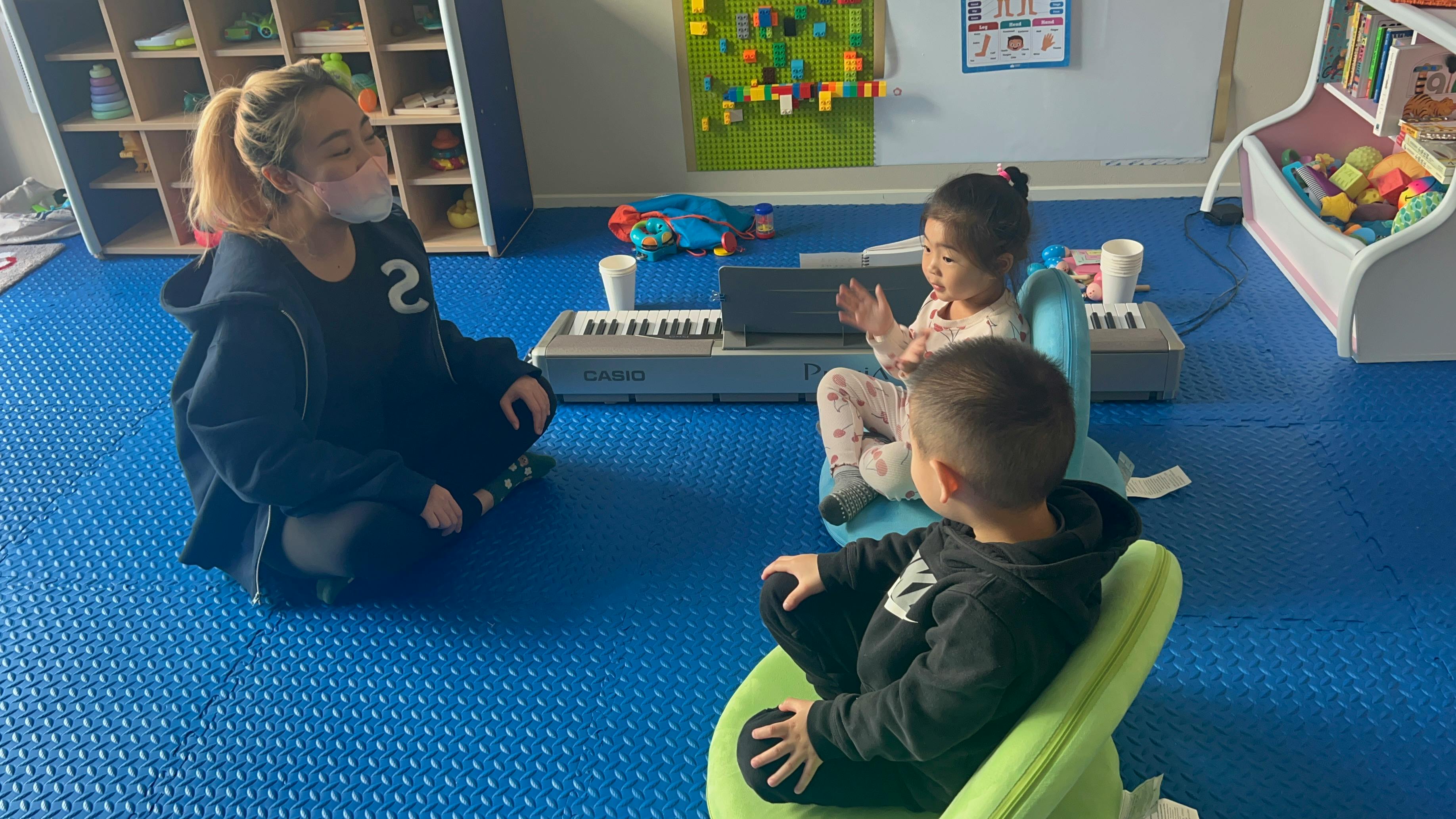 Person and two children sitting on floor with toy keyboards