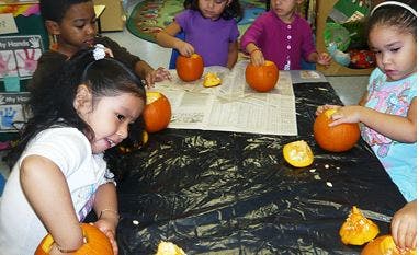 Children carving pumpkins at a table