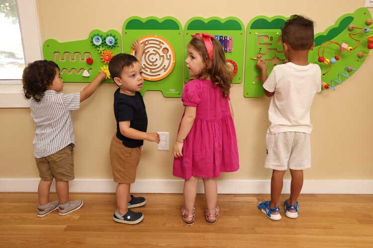 Four children playing with wall-mounted activity boards
