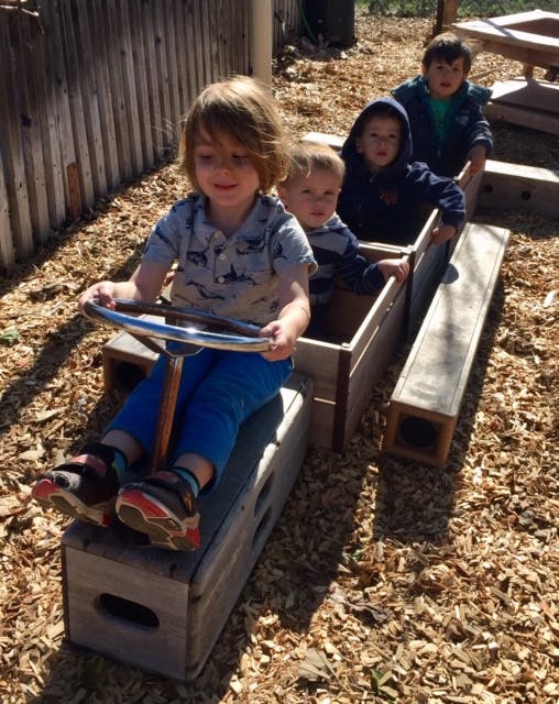 Children playing in wooden boxes on wood chips