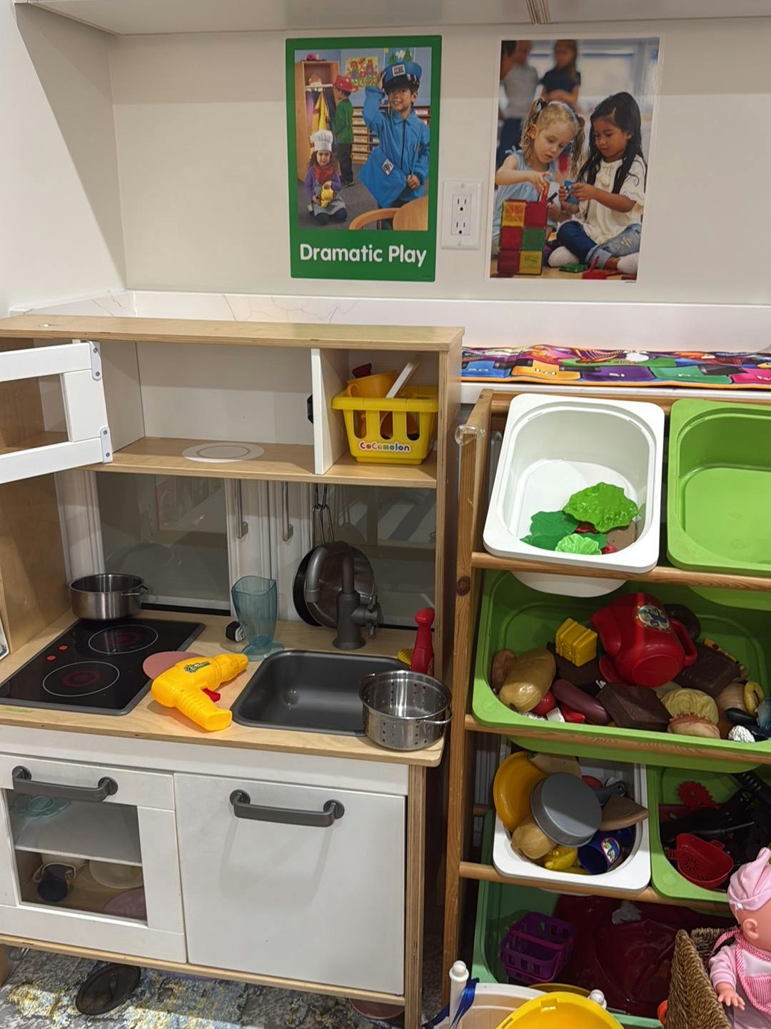Play kitchen and storage bins with toy food in a classroom setting