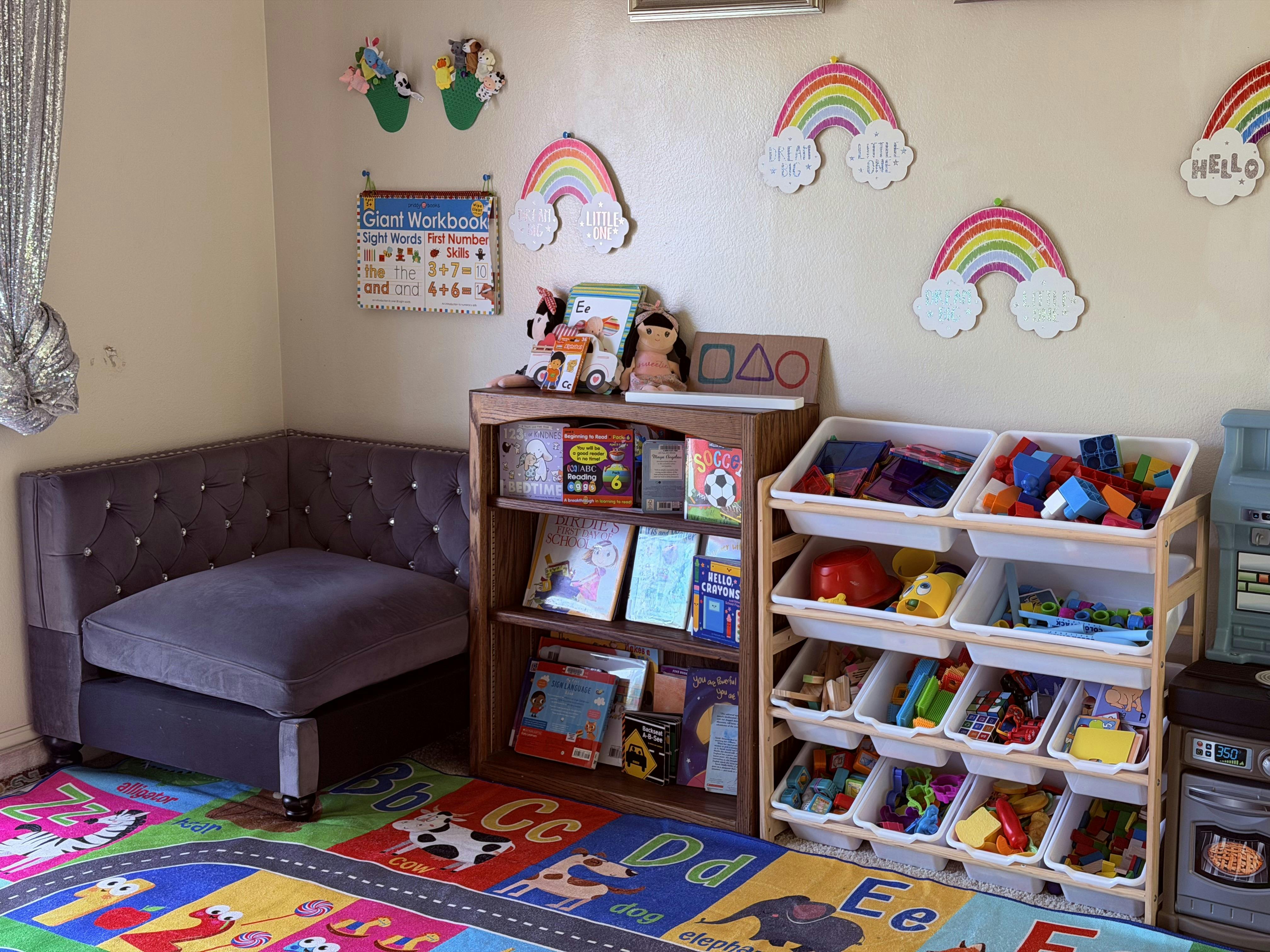 A children's reading nook with a bookshelf, toy storage, and alphabet rug