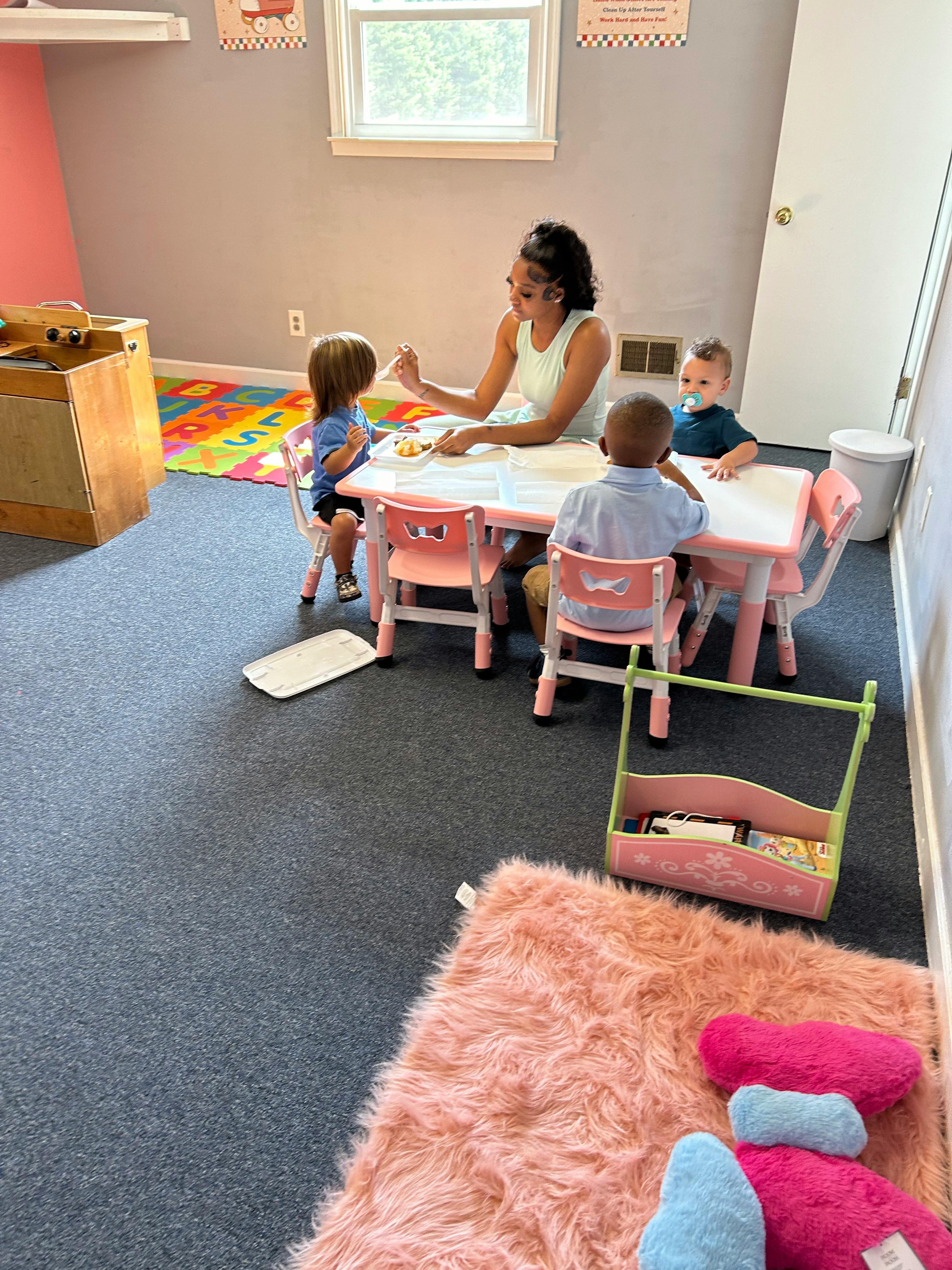 Person and three children sitting at a small table