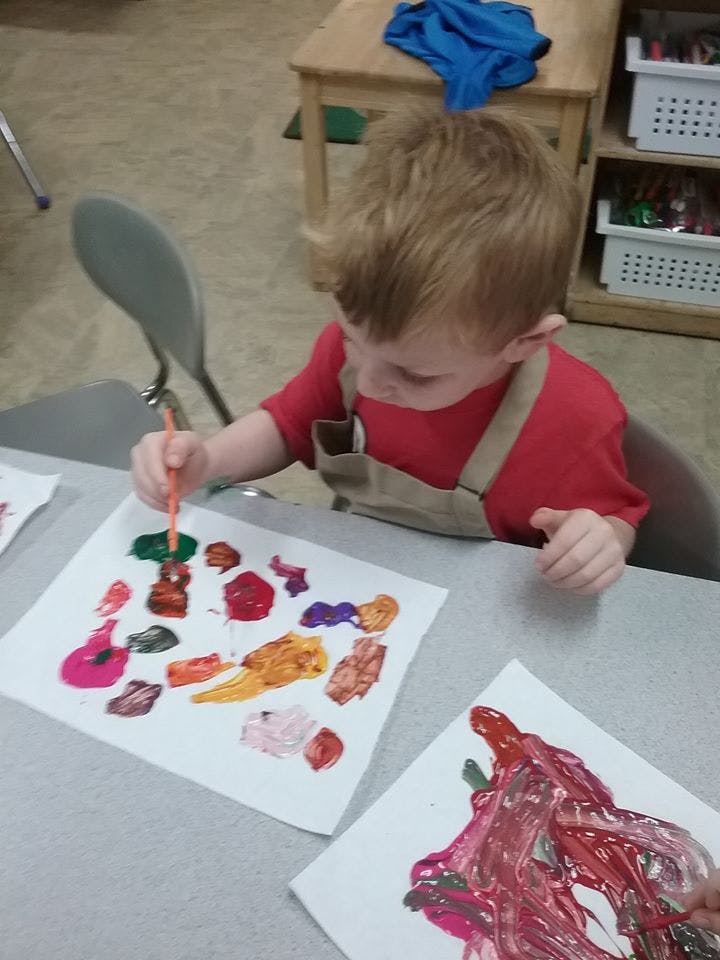 Child painting on paper in a classroom