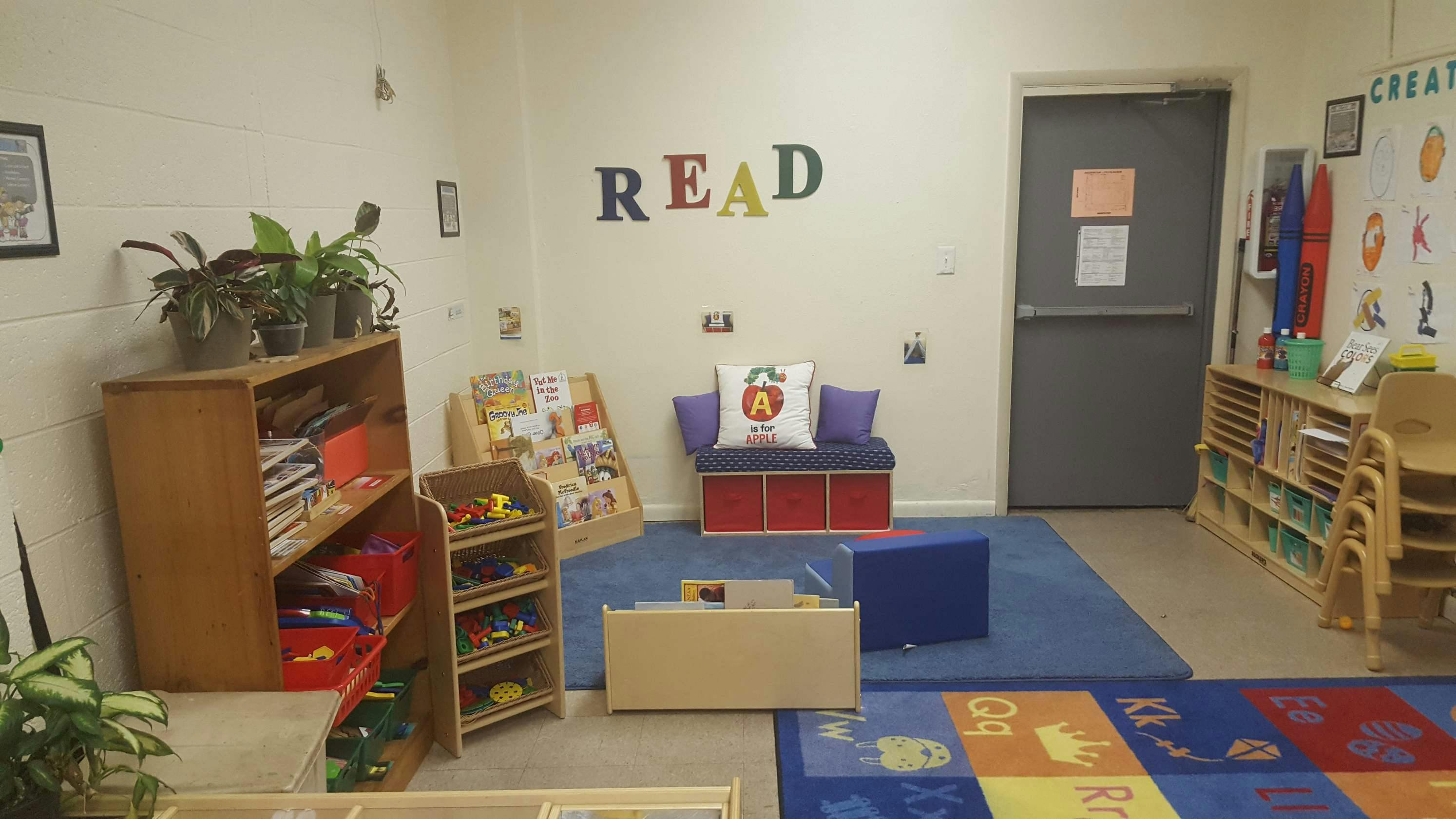 Classroom with shelves, chairs, and a rug with letters