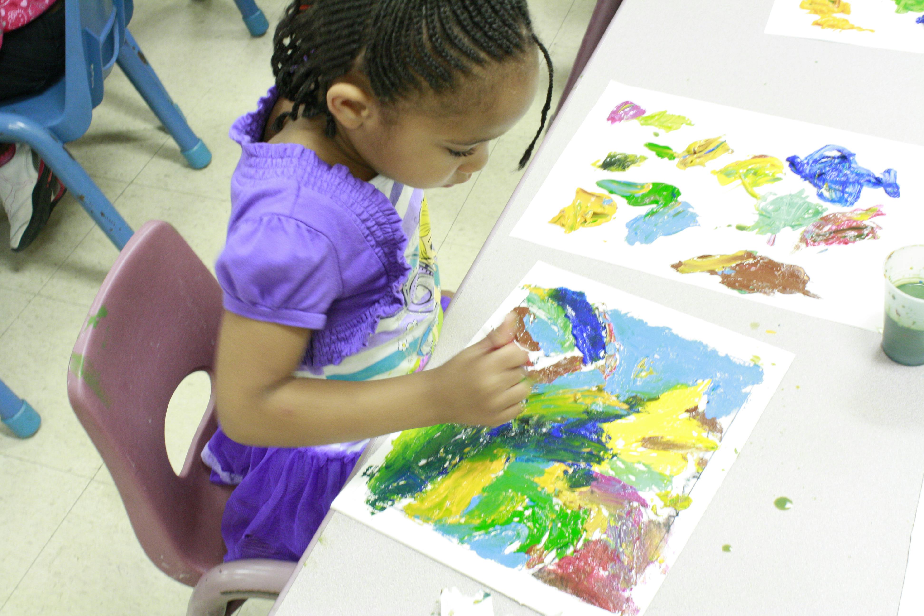 Child painting at a table in a classroom