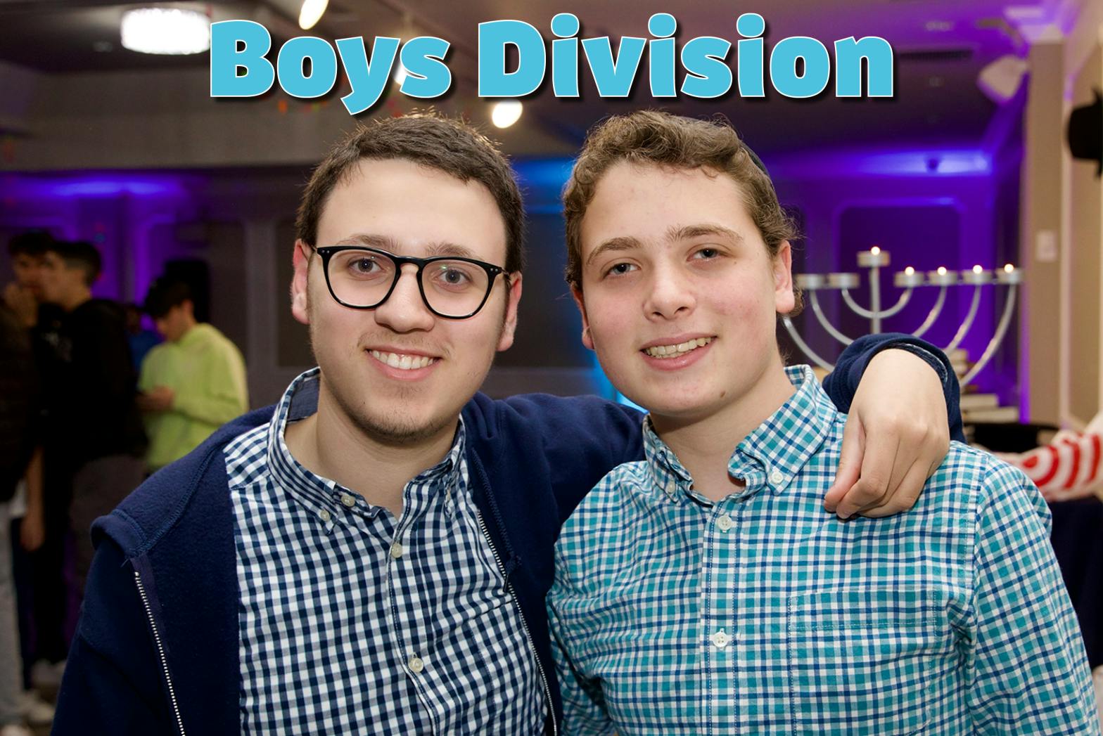 two young men smiling at the camera, one with glasses and arm around the other