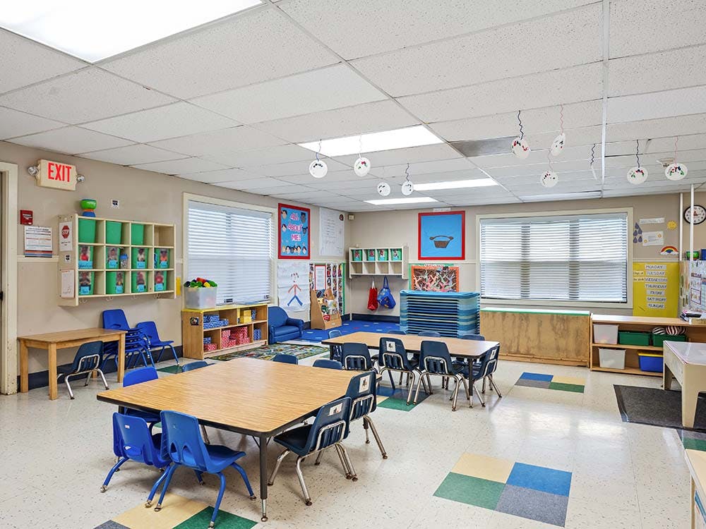 Classroom with small tables and chairs, shelves, and decorations