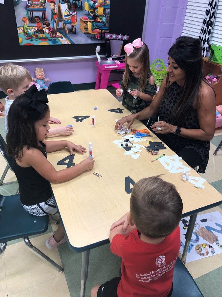 Adult and children at a table doing crafts in-class activity