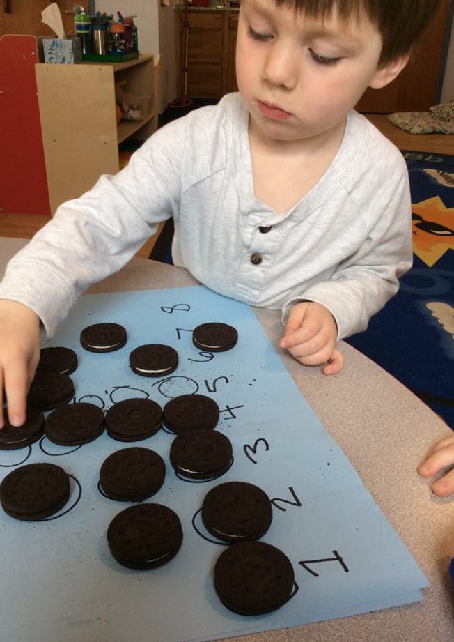 Child placing cookies on a blue paper with numbers