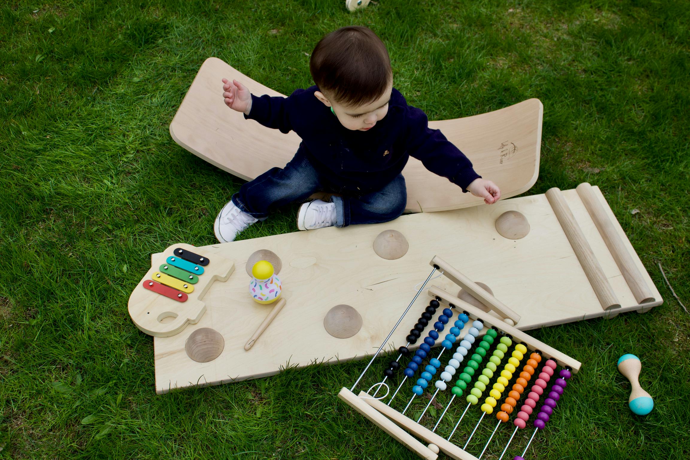 Child playing with wooden toys on a mat on grass