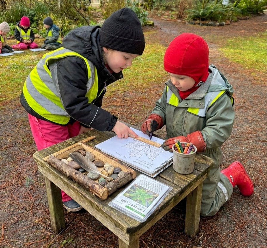 Child coloring a leaf drawing while another child points at the page