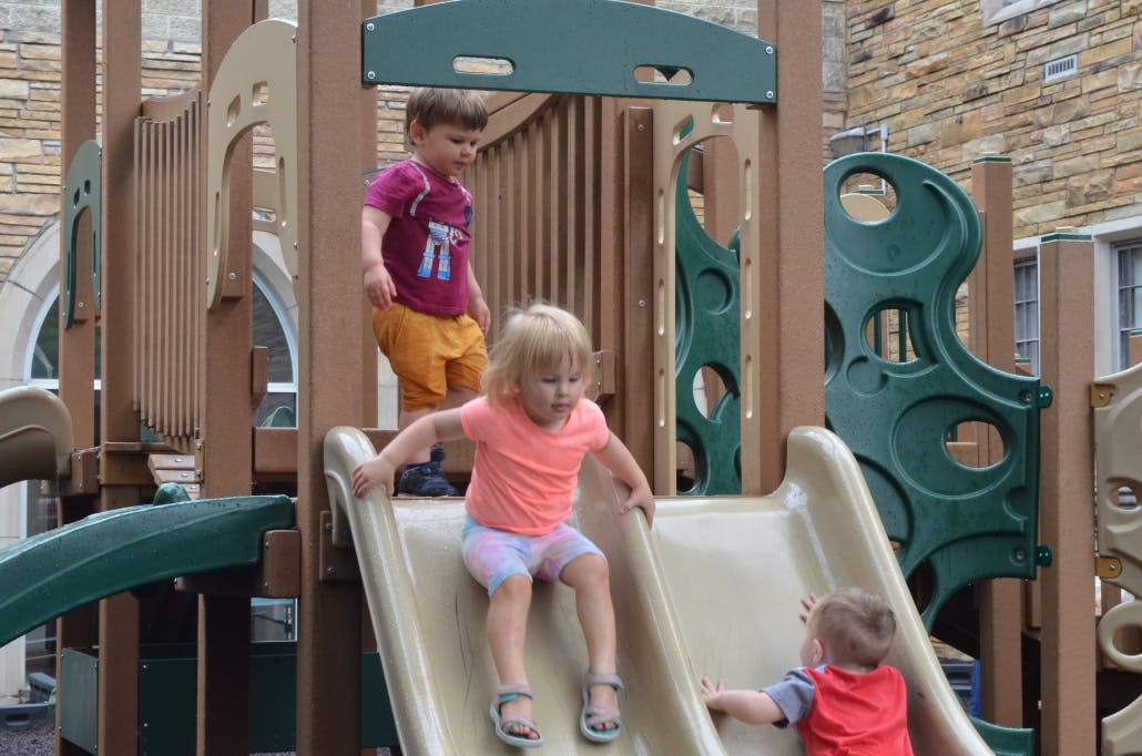 Three children playing on a playground slide structure