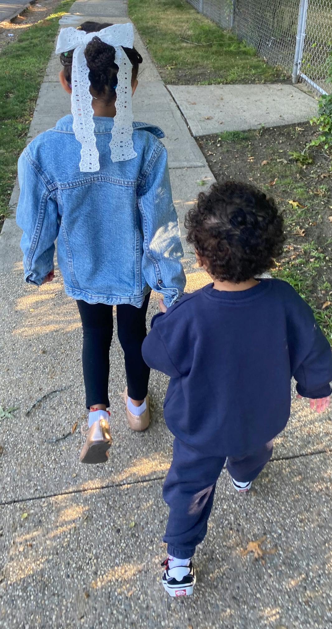 Two children walking on a sidewalk