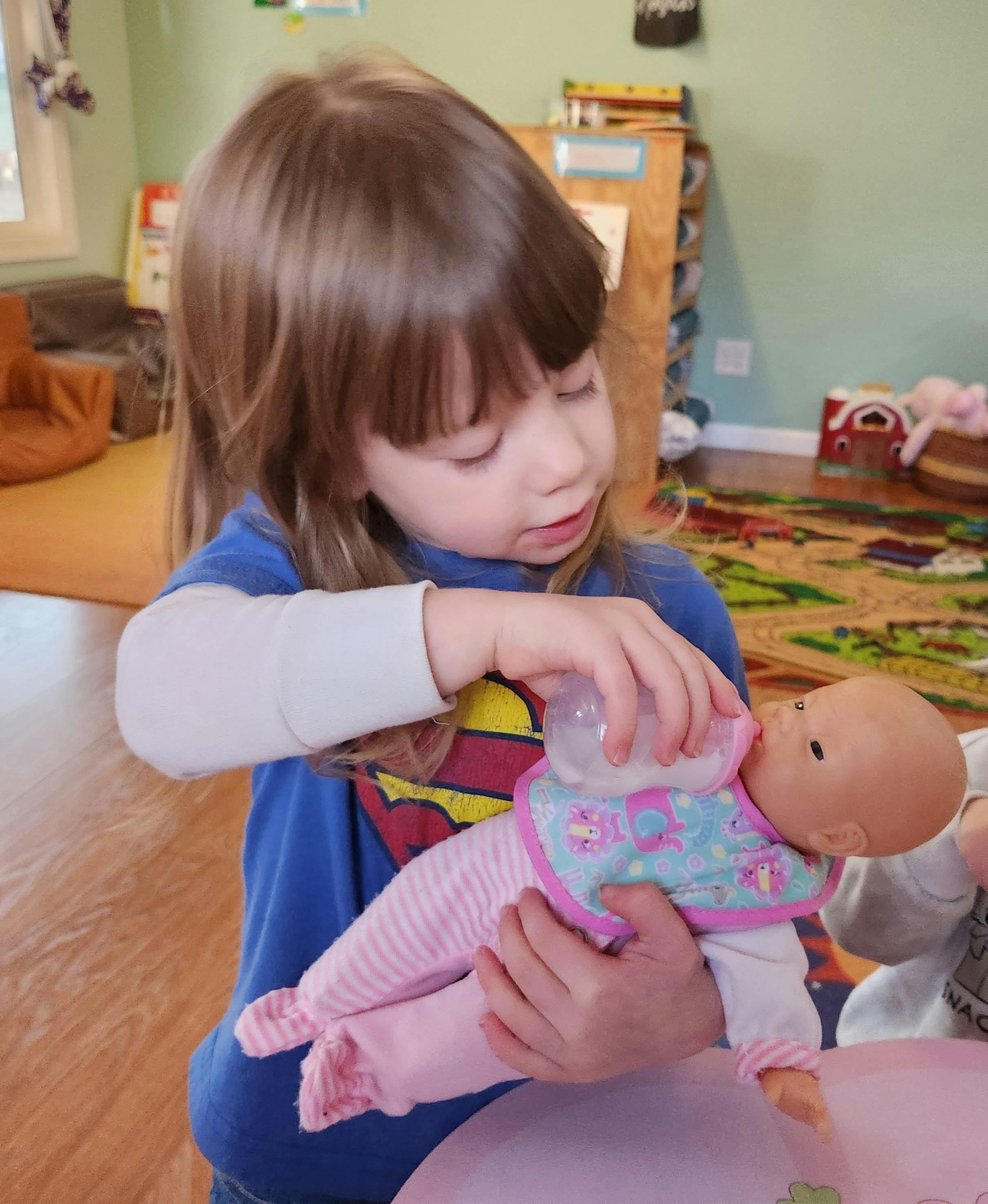 Child feeding a baby doll with a bottle