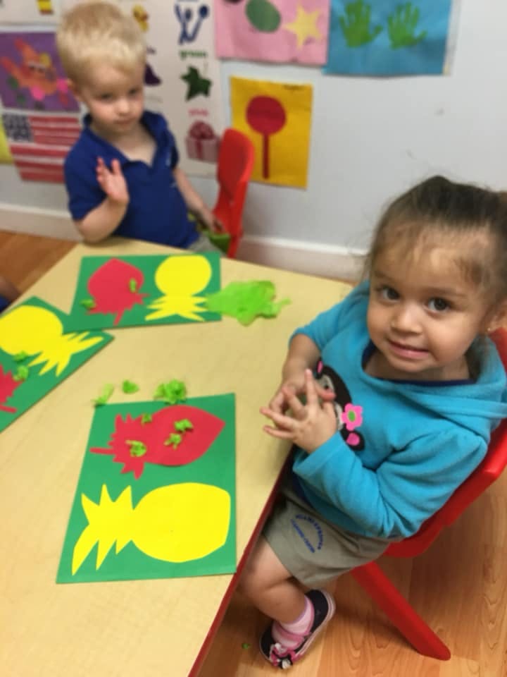 Two children at a table with fruit-themed crafts