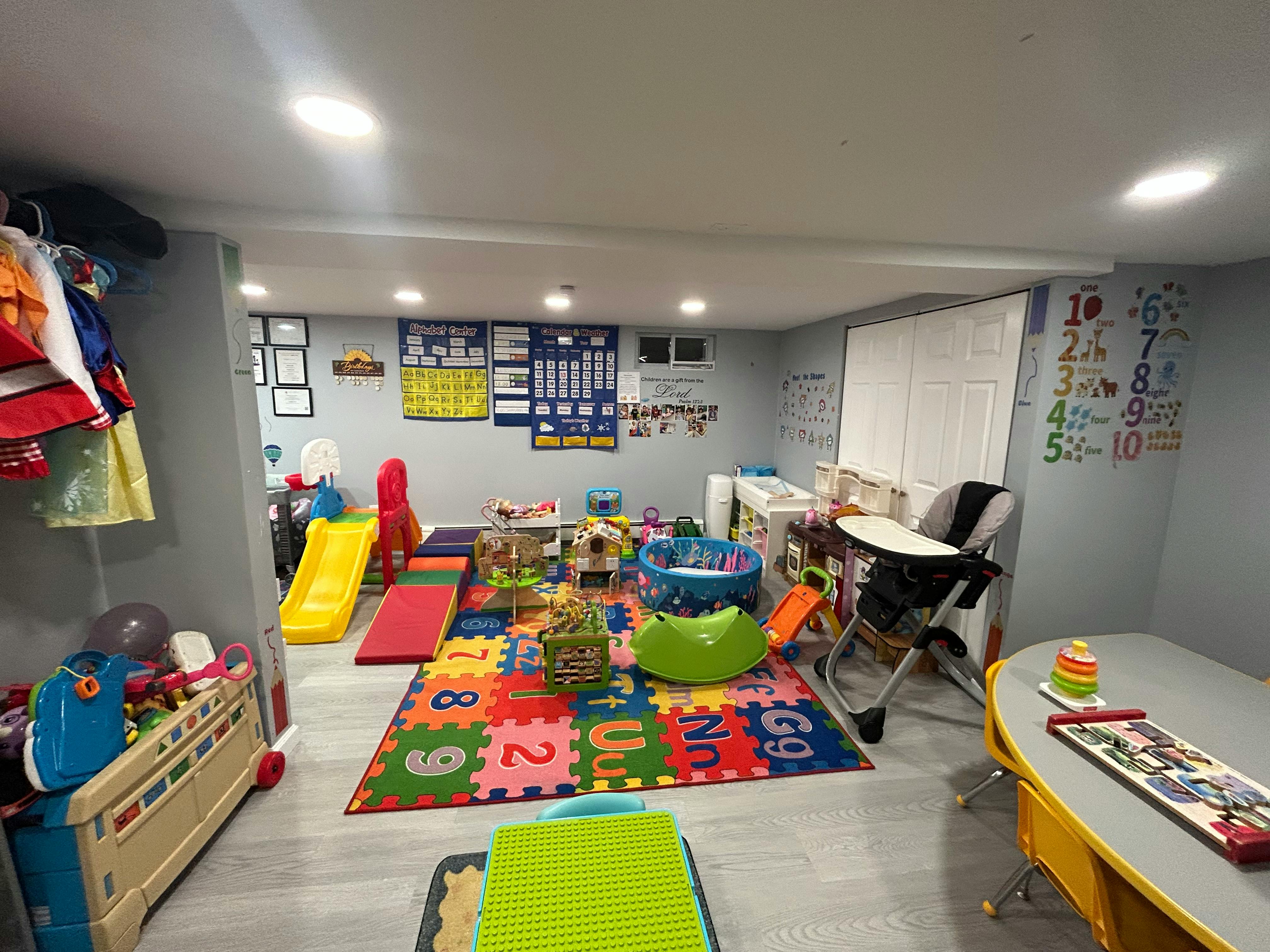 Playroom with colorful alphabet mat, slide, and various toys