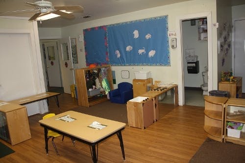 Classroom with tables, chairs, and a blue bulletin board