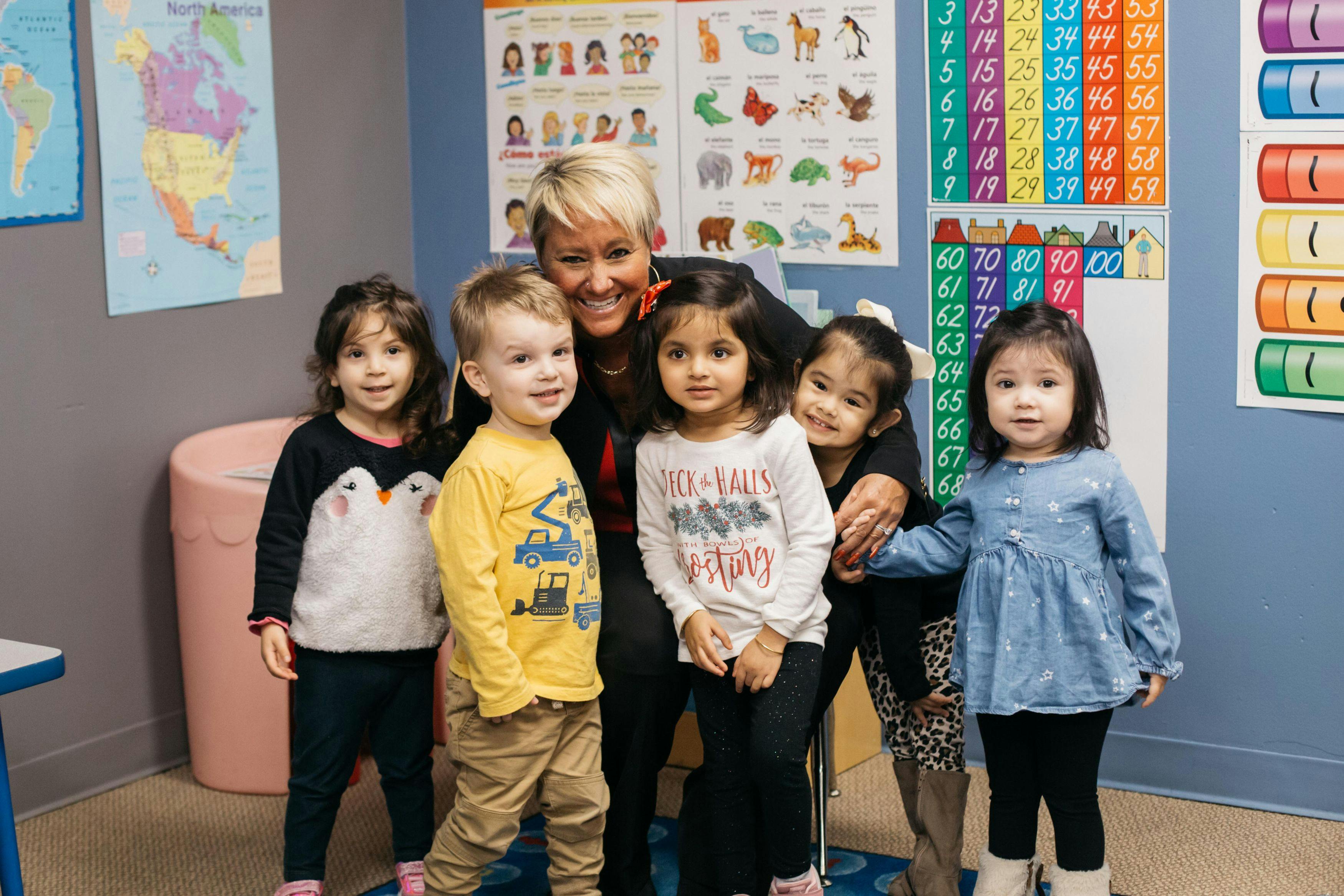 Adult person with four children and one teen in a classroom