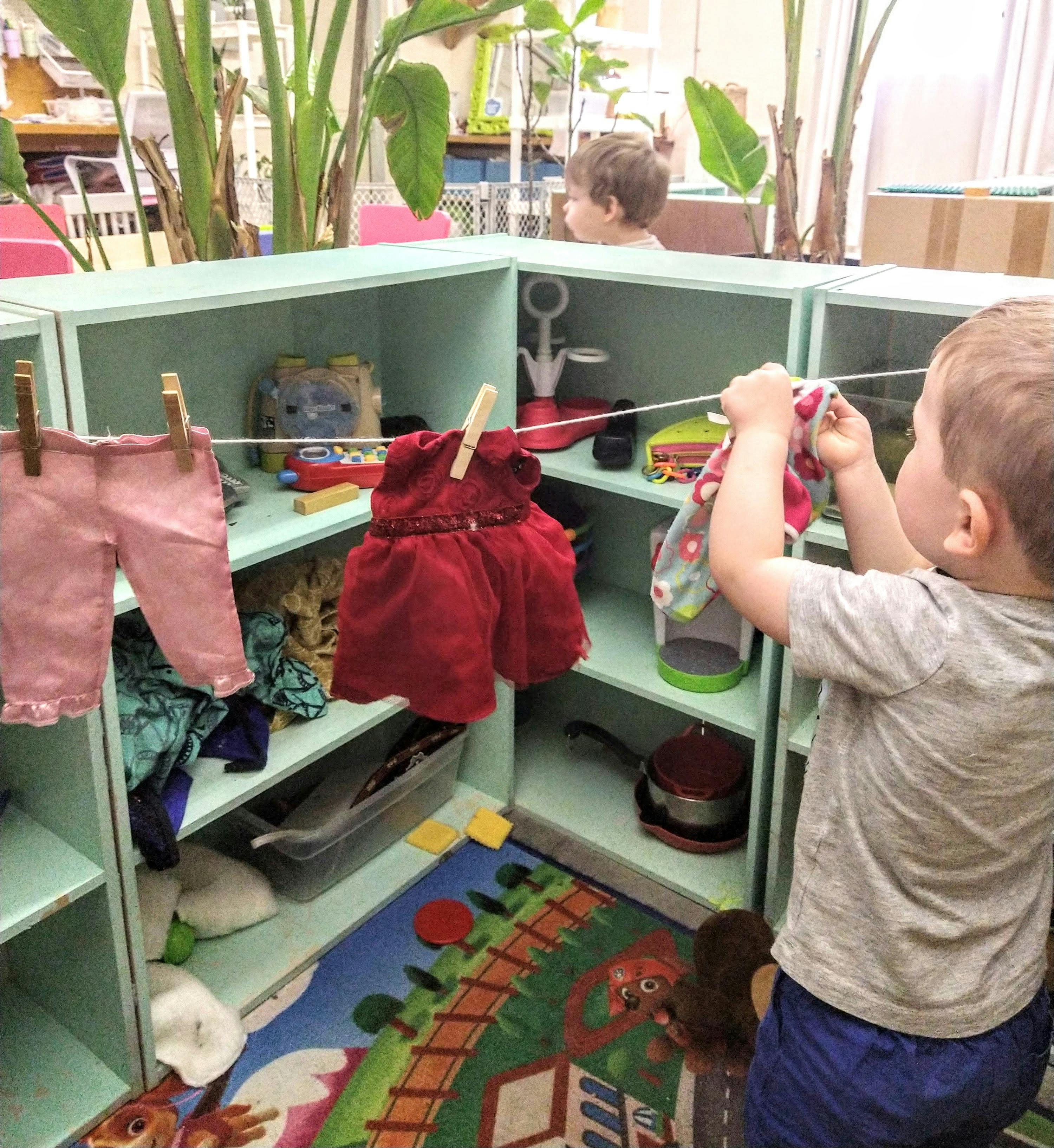 Child hanging clothes on a clothesline in a play area