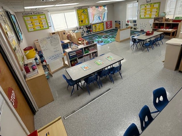 Classroom with child-sized tables and chairs, learning materials on walls and shelves