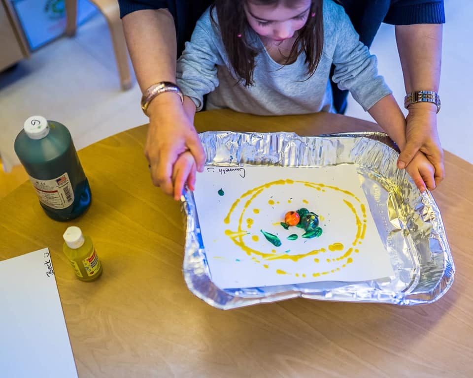 Adult and child holding a tray with a painted paper