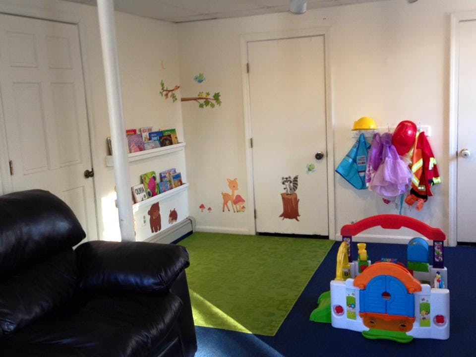 Playroom with a bookshelf, toy house, and coats hanging on a wall