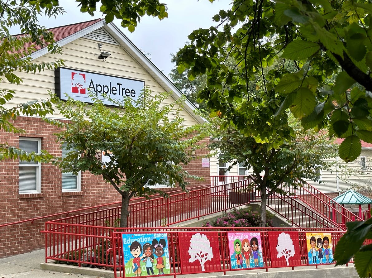 AppleTree building exterior with a red ramp and fence with children's drawings on a fence