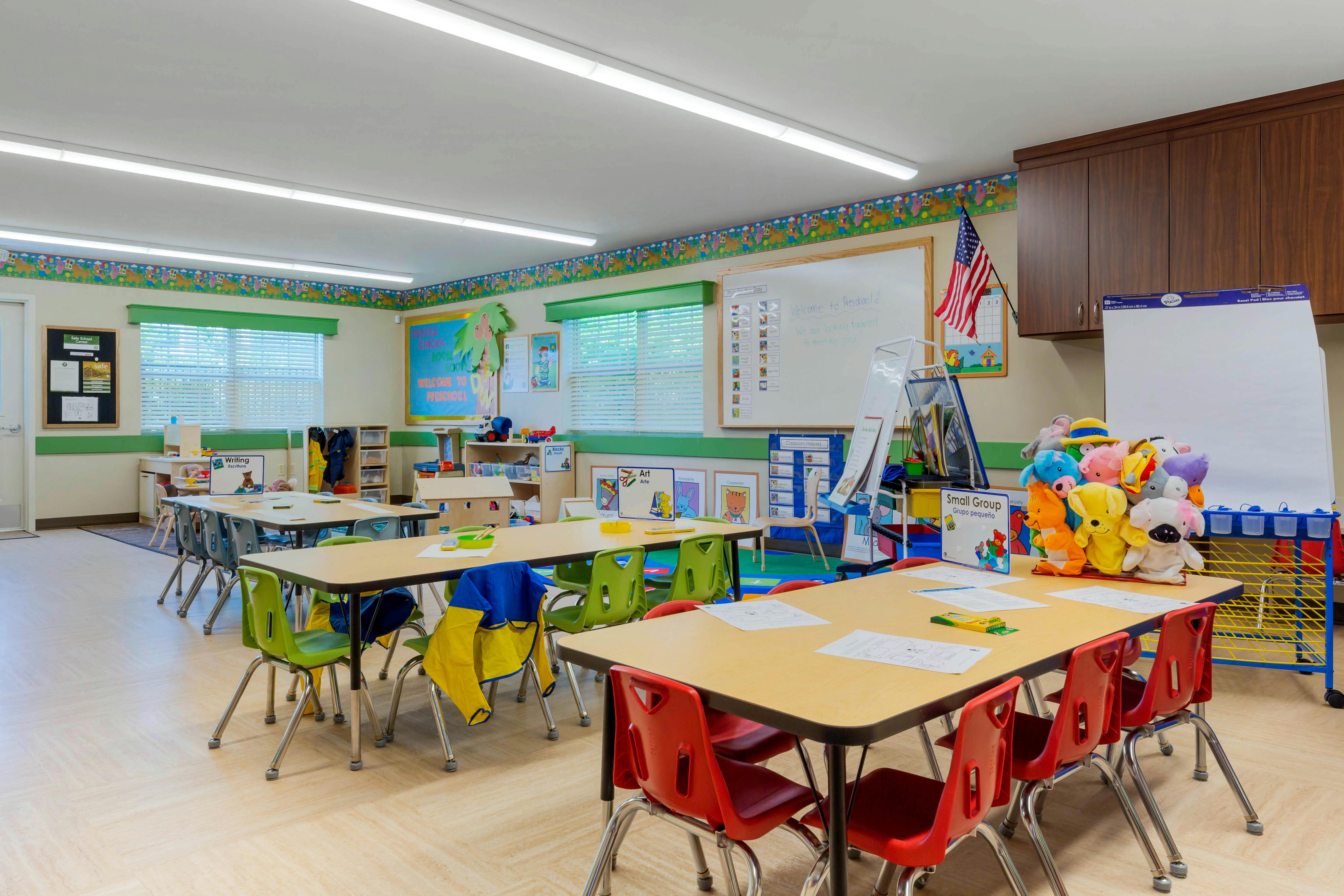 Empty preschool classroom with small tables and chairs
